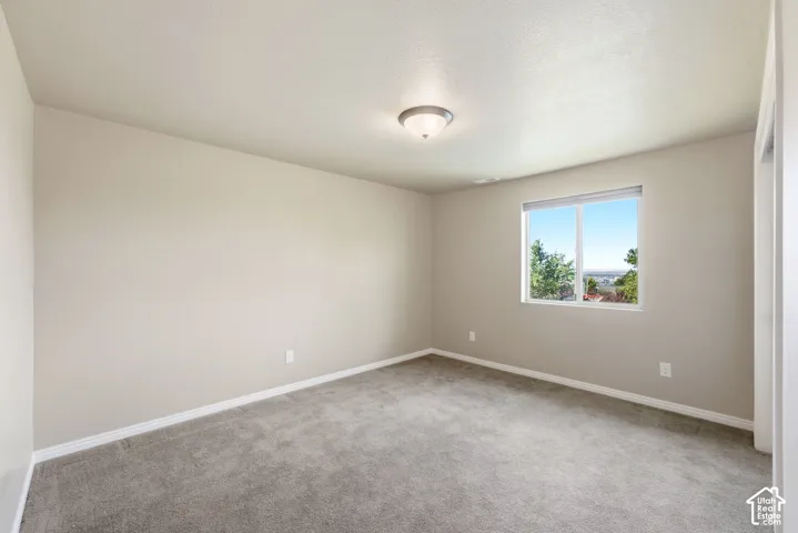 Neutral painted walls, gray carpet flooring, white window trim, and a semi-flush mount ceiling light