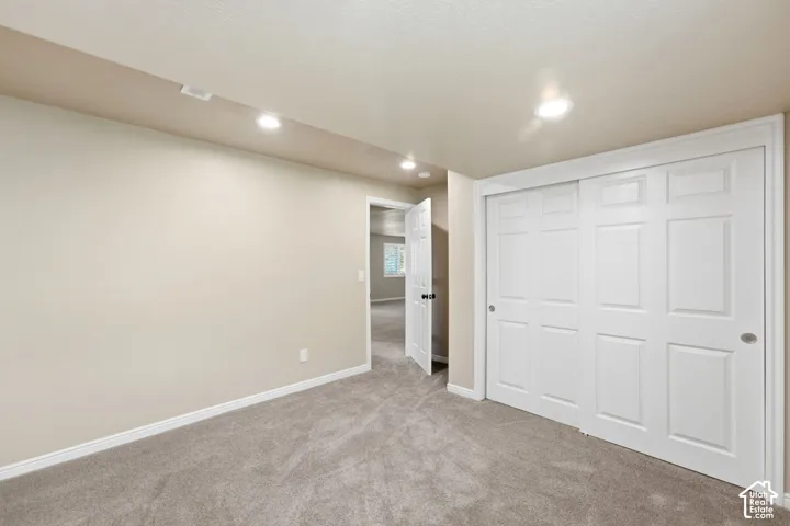 Neutral paint palette, recessed ceiling lighting, light-toned carpeting, white trim, and a built-in closet with sliding panel doors