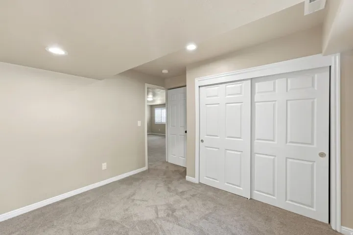 Recessed lighting, light-toned walls, and grey carpeting