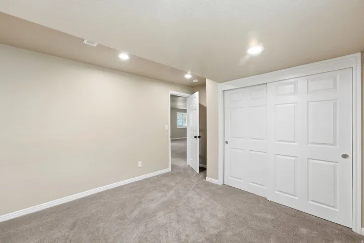 Neutral paint palette, recessed ceiling lighting, light-toned carpeting, white trim, and a built-in closet with sliding panel doors