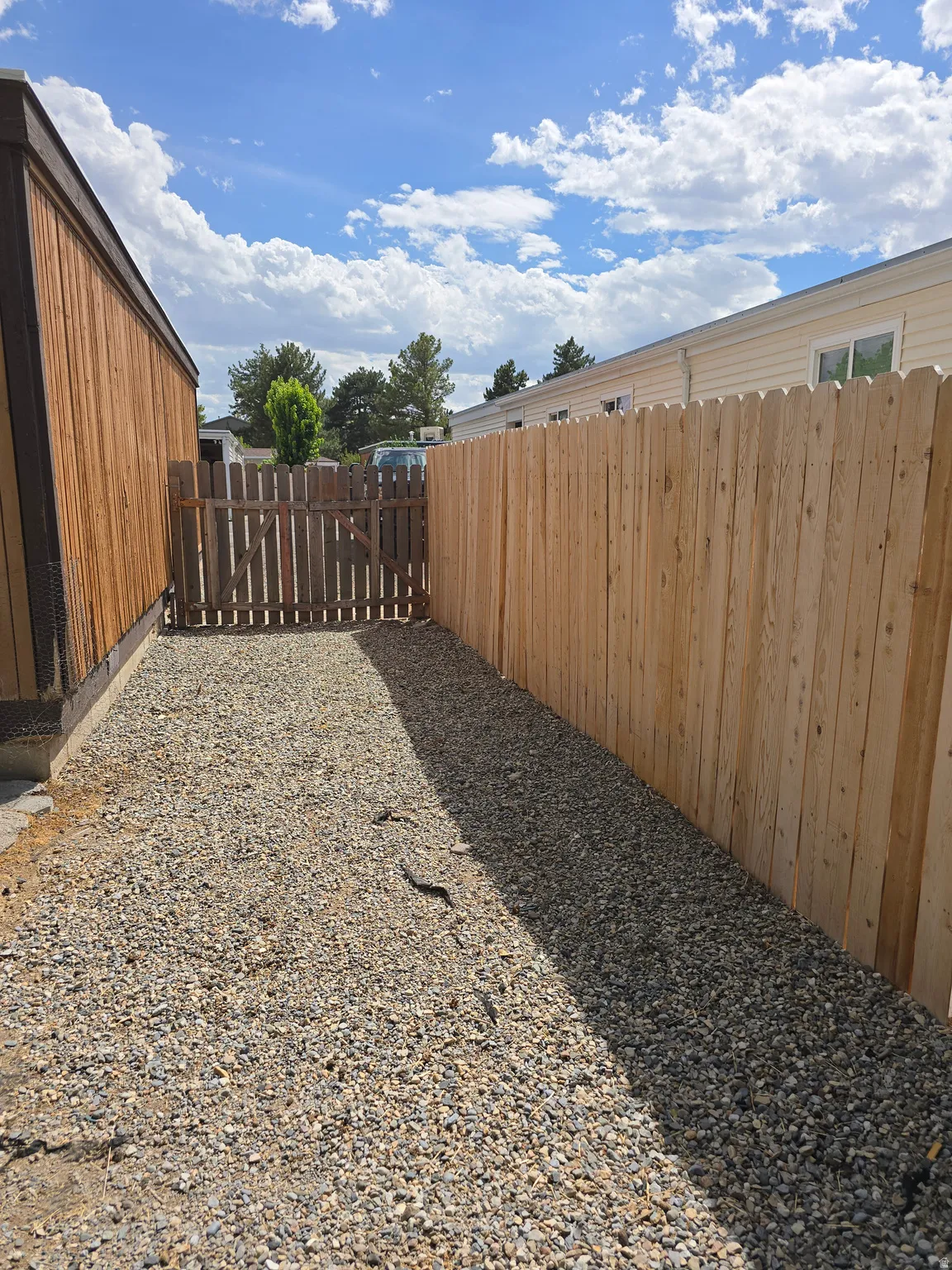 Gravel pathway with a wood privacy fence and a separate wood gate