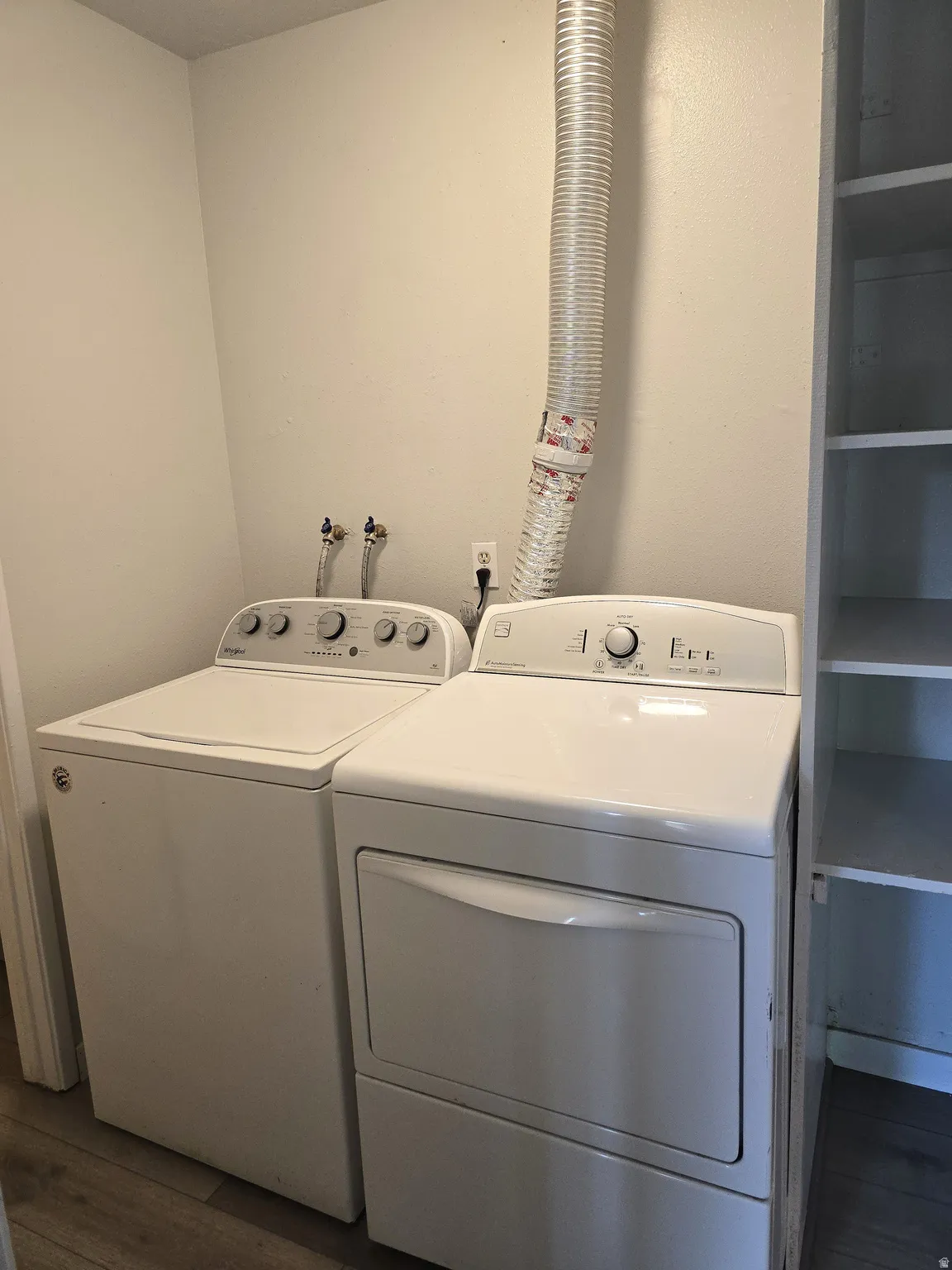 White washer and dryer units, utility connections, and built-in shelving