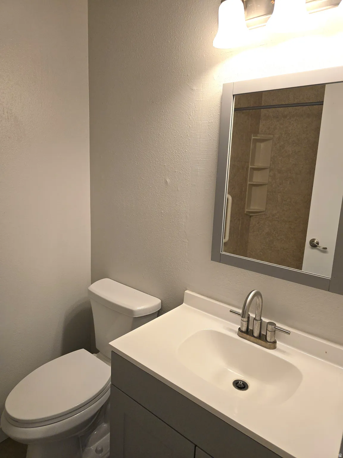 Vanity with an integrated sink, brushed nickel faucet, and mirror with a coordinating frame