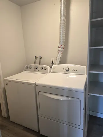 White washer and dryer units, utility connections, and built-in shelving