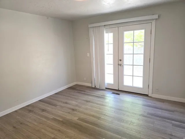 Wood-finish flooring, white walls, and white French doors with integrated window panes