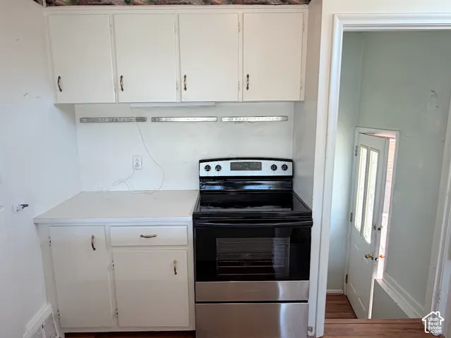 White cabinetry with minimalist hardware, integrated electric range, and laminate countertop
