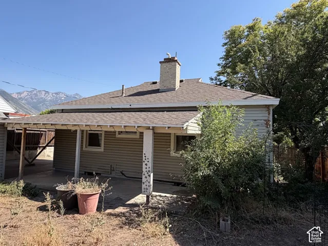 Covered patio area, horizontal siding exterior, visible roofline, brick chimney, distant mountain scenery