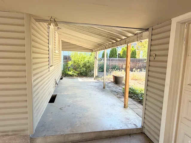 Covered outdoor patio with concrete flooring, supported by wooden posts