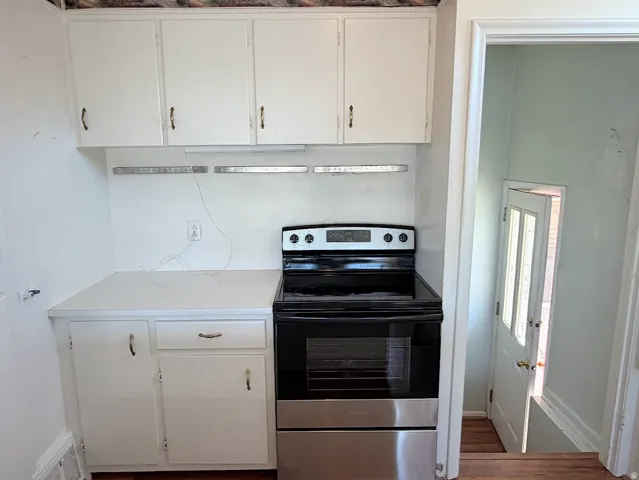 White cabinetry with minimalist hardware, integrated electric range, and laminate countertop