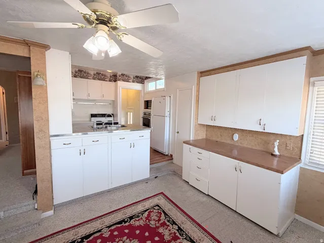 Recessed lighting, stainless steel sink with gooseneck faucet, white cabinetry, and a ceiling fan