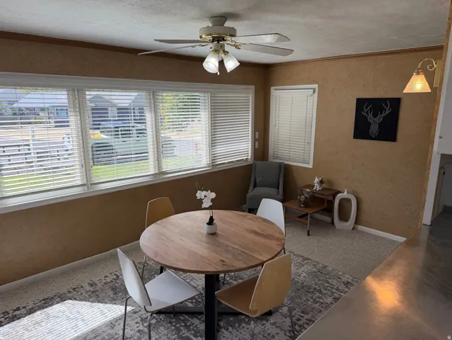 Dining area with multiple windows, textured wall finish, and a ceiling fan with integrated lighting
