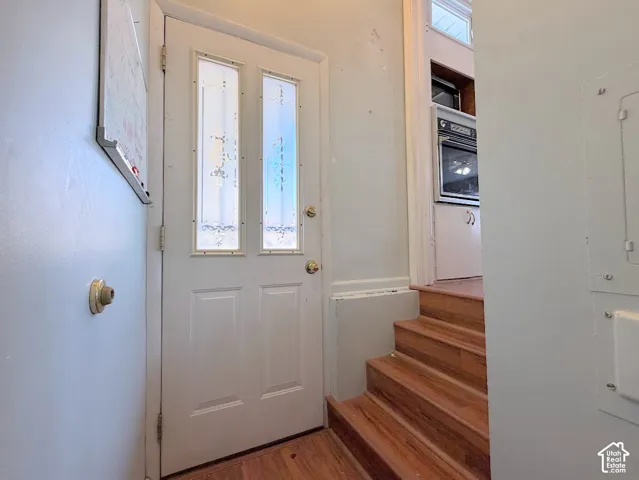 Entryway featuring a white door with decorative glass inserts, wood-finish stairs, and a built-in oven