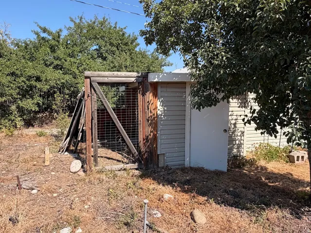 Siding-clad utility structure with a single entry door and a wooden, fenced enclosure