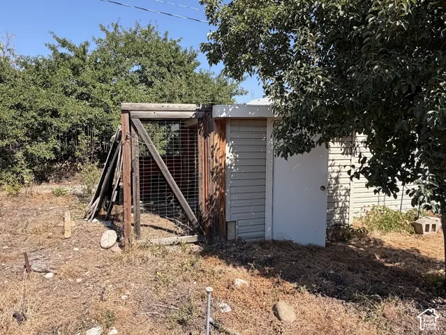 Siding-clad utility structure with a single entry door and a wooden, fenced enclosure