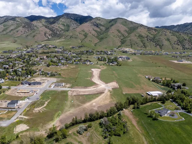 Expansive land parcels with established road infrastructure, surrounded by a mountain backdrop and existing residential development