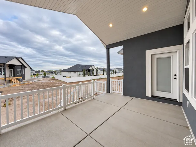 Covered patio with a concrete surface, white railing, and recessed lighting