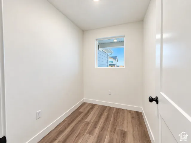 Compact room with wood-finish flooring, white walls, and a single window