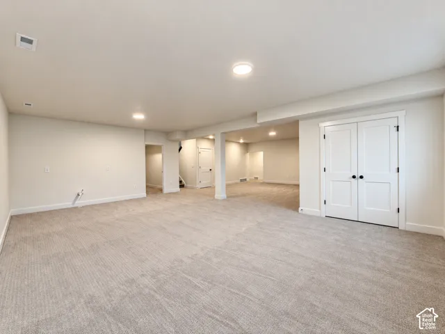 Expansive room featuring light-toned carpeting, recessed ceiling lighting, and multiple distinct areas