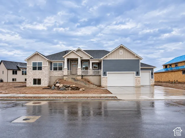 Stone facade with fiber cement siding, attached two-car garage, covered porch, and dark shingle roof