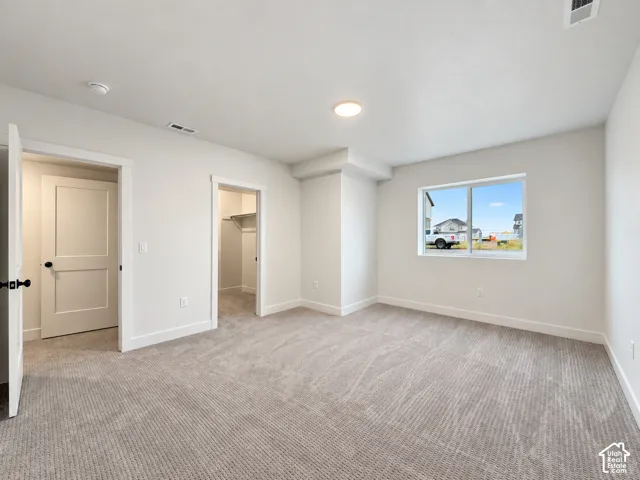 Recessed lighting, light gray wall paint, textured carpeting, panel doors, and a window with white trim