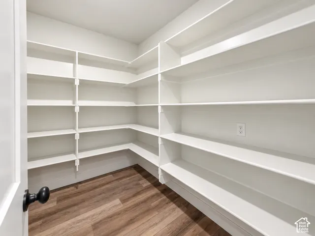 Extensive built-in white shelving, wood-finish flooring, and a matte black door handle
