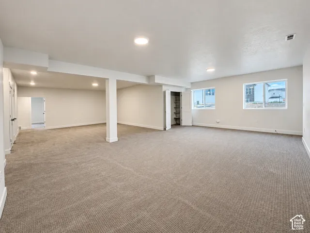 Spacious room with plush carpet flooring, recessed lighting, and white walls