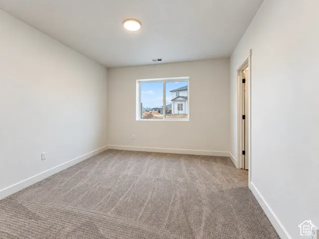 Neutral-toned carpet flooring, white painted walls, and a single window with white trim