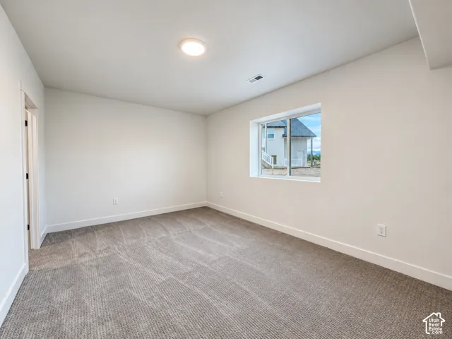 Carpeted room featuring a window with exterior visibility, white walls, white trim, and a ceiling-mounted light fixture