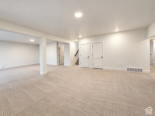 Expansive carpeted area with recessed lighting, white walls, and white trim