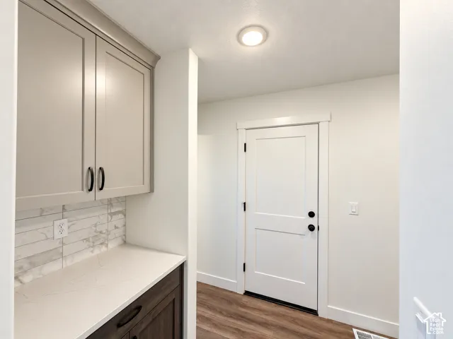 Built-in cabinetry with light-toned upper cabinets, a light-toned countertop, and a tiled backsplash