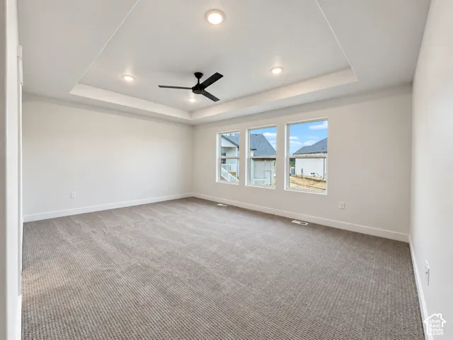 Recessed lighting, tray ceiling, ceiling fan, carpeted flooring, and multiple windows