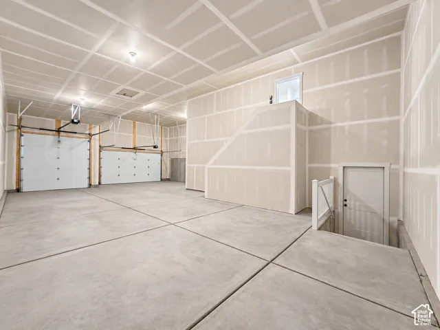 Spacious garage featuring two overhead doors, concrete flooring, and an unfinished interior with exposed drywall