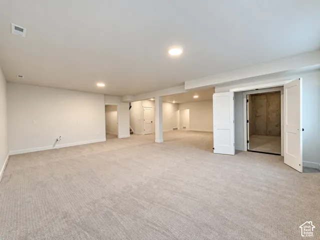 Spacious interior featuring neutral carpeting, recessed lighting, and white paneled doors