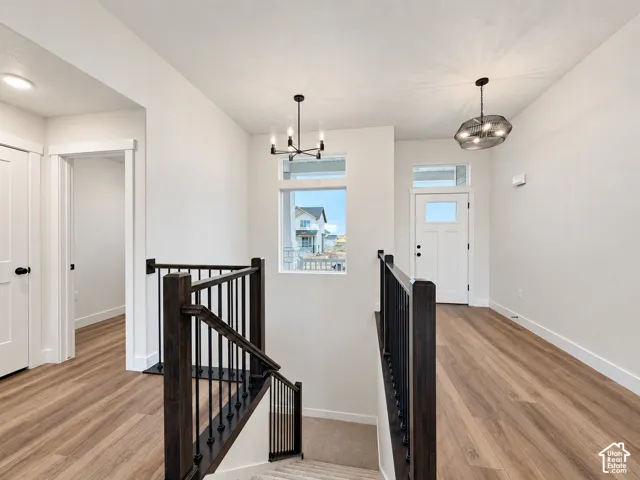 Wood-finish flooring throughout, modern lighting fixtures, white paneled doors, and dark wood stair railing