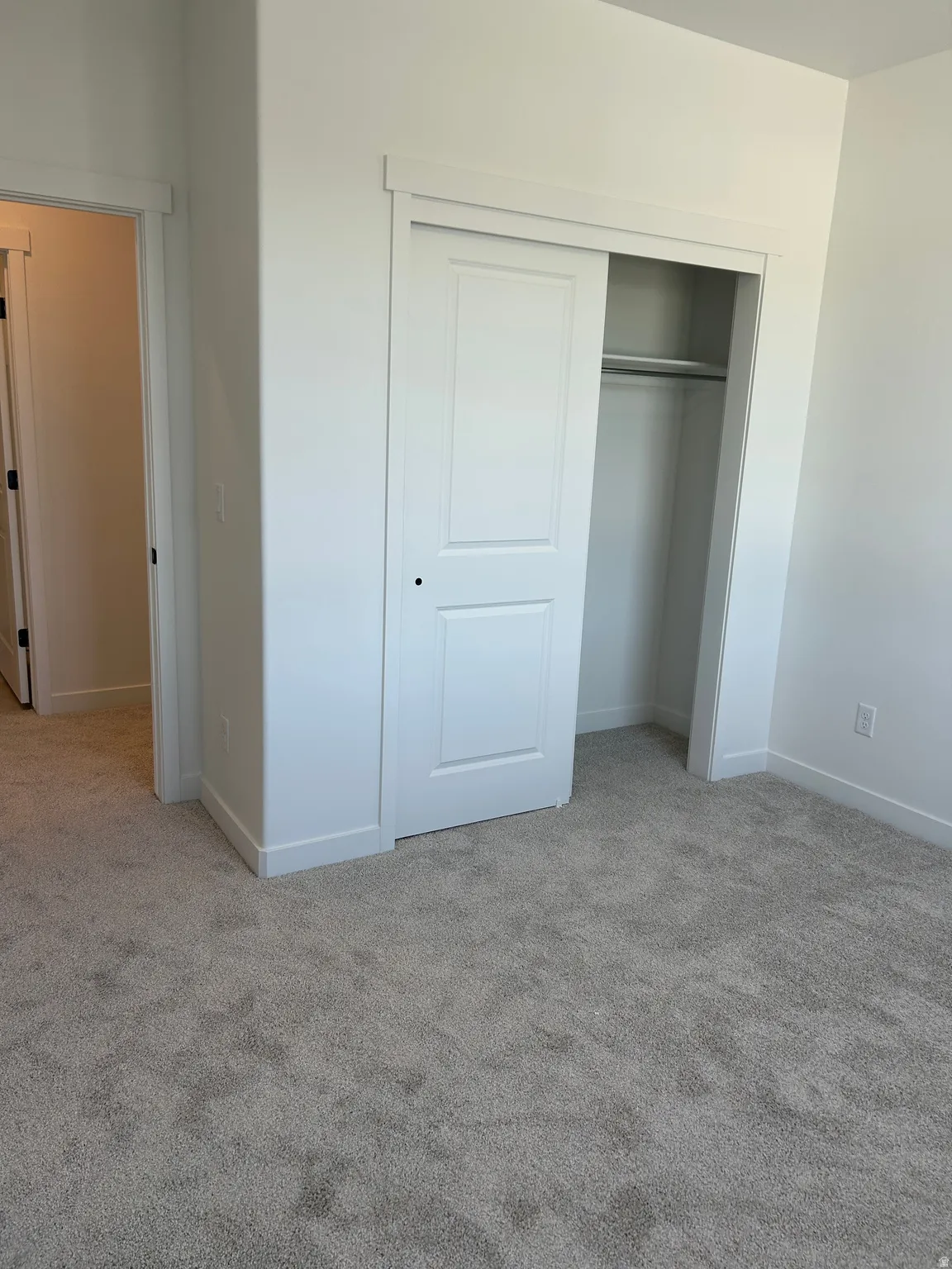 Sliding closet doors, gray carpeting, and white trim
