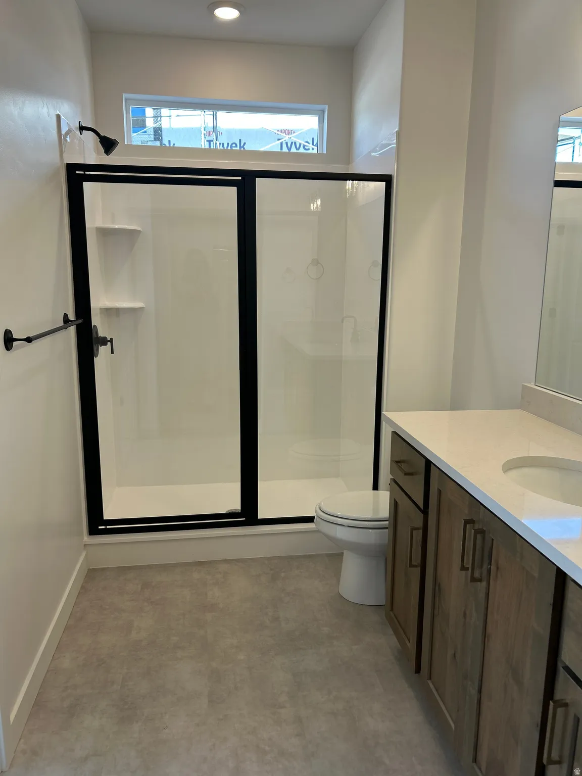 Shower with black-framed glass enclosure, white composite shower surround, and black fixtures