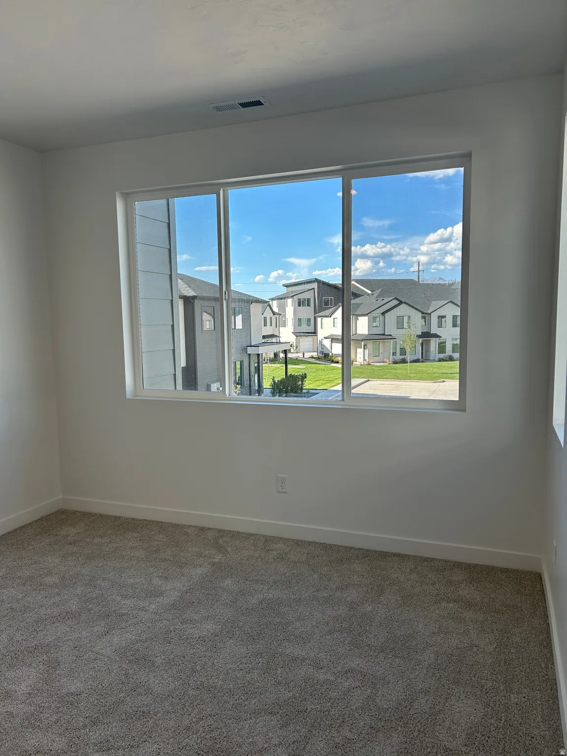 Carpeted flooring, white painted walls, and a large window with multiple panes