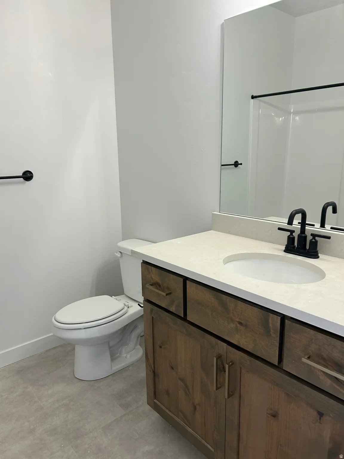 Wood-finish vanity with a light-toned countertop and an integrated sink, featuring a matte black faucet