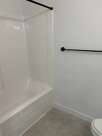 Bathtub with integrated shower surround, dark-finish shower rod, and coordinating dark-finish towel bar