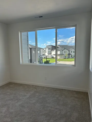 Carpeted flooring, white painted walls, and a large window with multiple panes