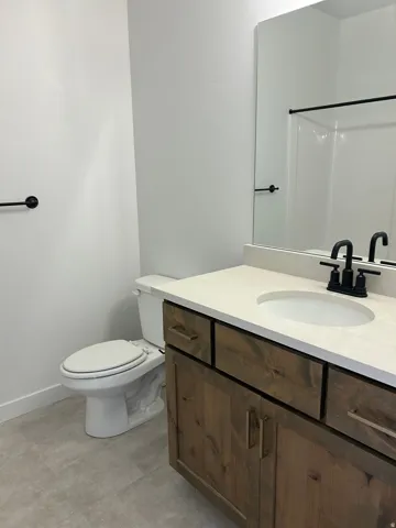 Wood-finish vanity with a light-toned countertop and an integrated sink, featuring a matte black faucet