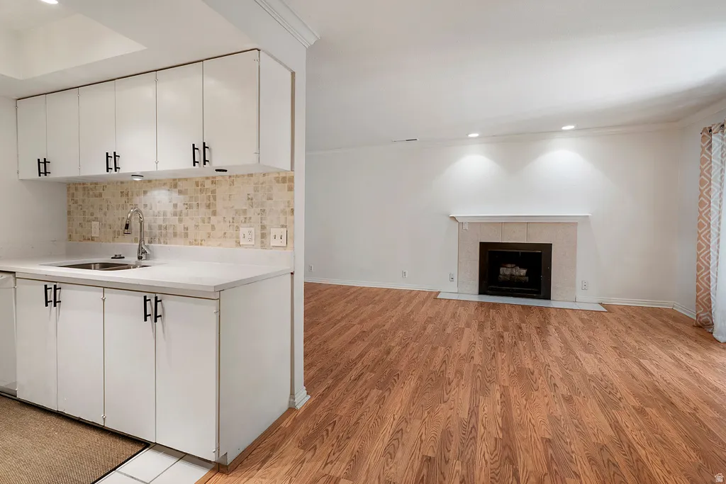 White cabinetry with matte black hardware, integrated sink, and mosaic tile backsplash