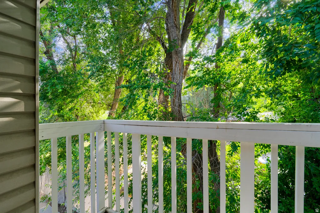 Private balcony with white railing and verdant tree canopy
