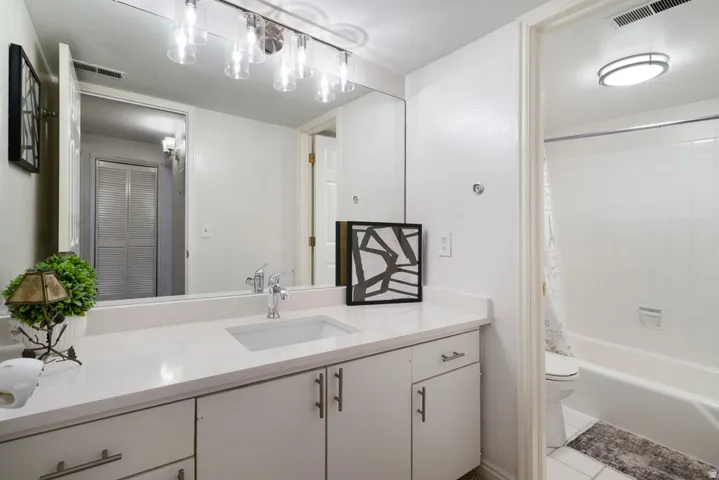 White vanity with an integrated rectangular sink, chrome faucet, and expansive wall mirror