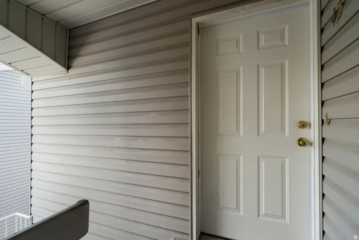 White paneled entry door with brass hardware, surrounded by horizontal siding