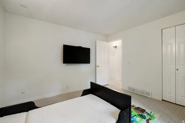 White walls, neutral carpet, recessed ceiling light, and bi-fold closet doors