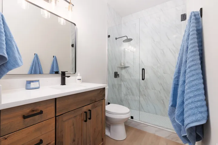 Custom wood-finish vanity with dark hardware, a white countertop, and an undermount sink