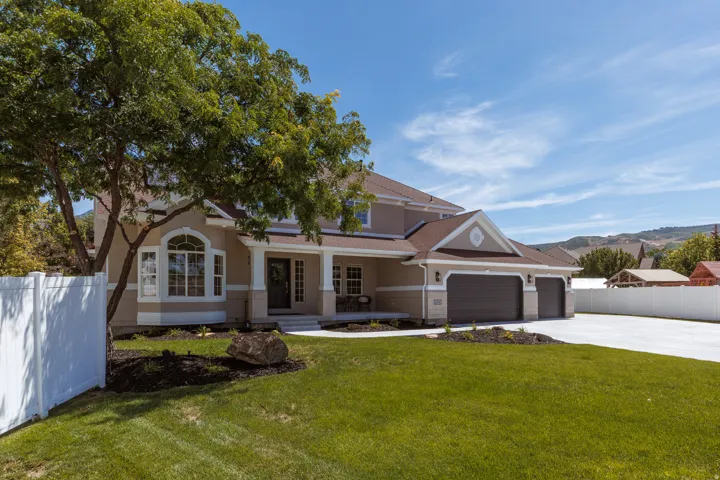 Stucco exterior with a covered porch, attached two-car garage, and a wide concrete driveway