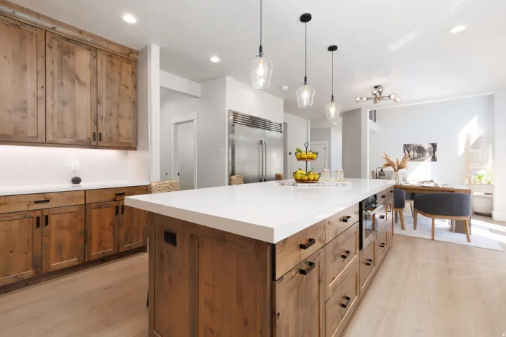 Kitchen featuring wood-finish cabinetry, a large kitchen island with a white countertop, stainless steel appliances, and light wood-finish flooring