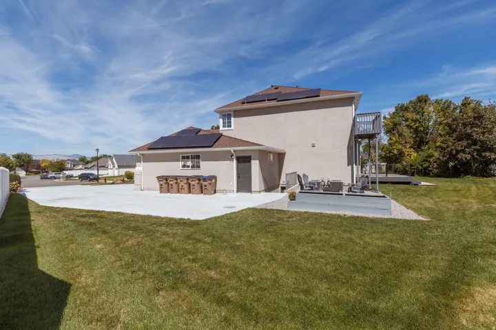 Expansive concrete patio, private deck, manicured lawn, and solar panels